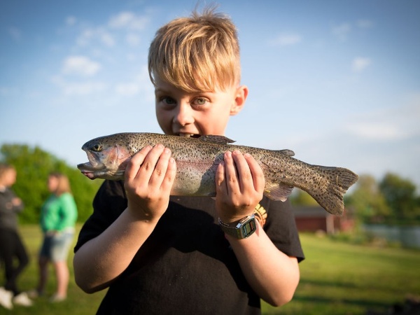 Glad dreng med friskfanget regnbue ørred i Ørsted Outdoor